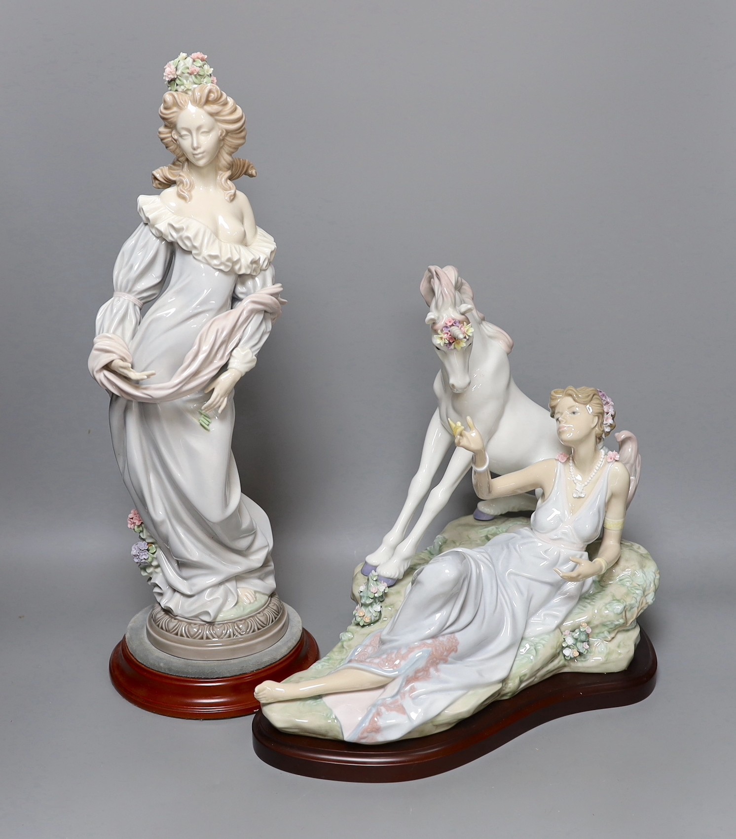 A Lladro figure of a lady and a similar figure group of a lady and a unicorn. Both on hardwood stands, tallest 41cm excluding stand